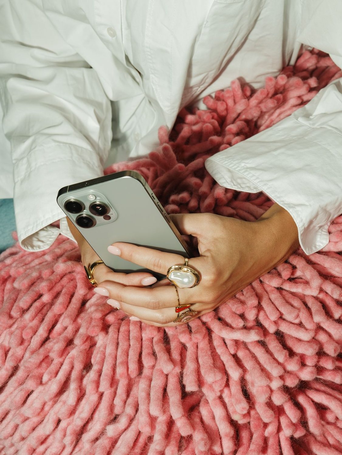 Handen met telefoon op een roze kleed