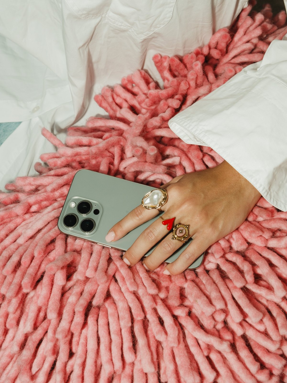 Hand met telefoon op een roze kleed